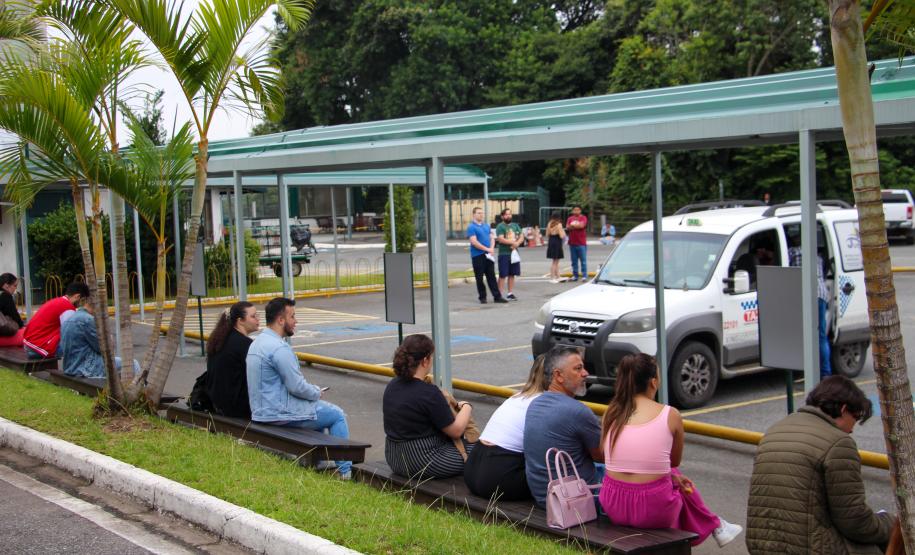 Imagem que mostra candidatos e candidatas sentados em frente ao prédio principal da Universidade Tuiuti, em Curitiba, um dos locais de prova.