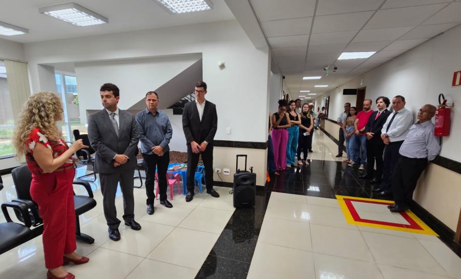 Imagem que mostra a inauguração da sala da DPE-PR em Cruzeiro do Oeste. Várias pessoas estão em pé, em um corredor e em uma pequena sala de recepção do Fórum, assistindo a solenidade.