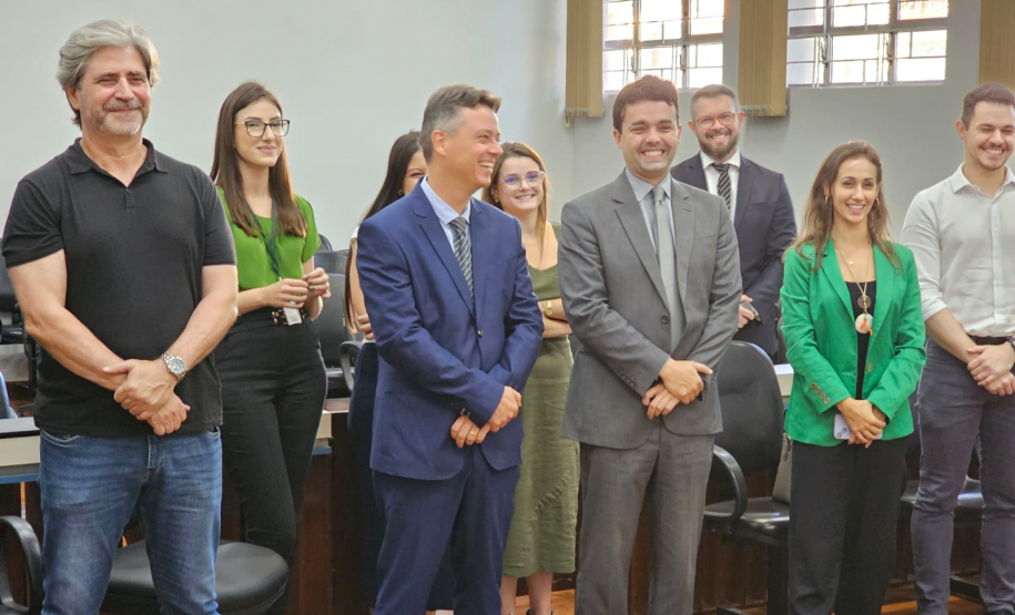 Imagem que mostra representantes da Defensoria e autoridades convidadas na inauguração da sala da DPE-PR em Jandaia. As pessoas, 4 mulheres e 5 homens, estão em pé, diante de cadeiras e todos riem.