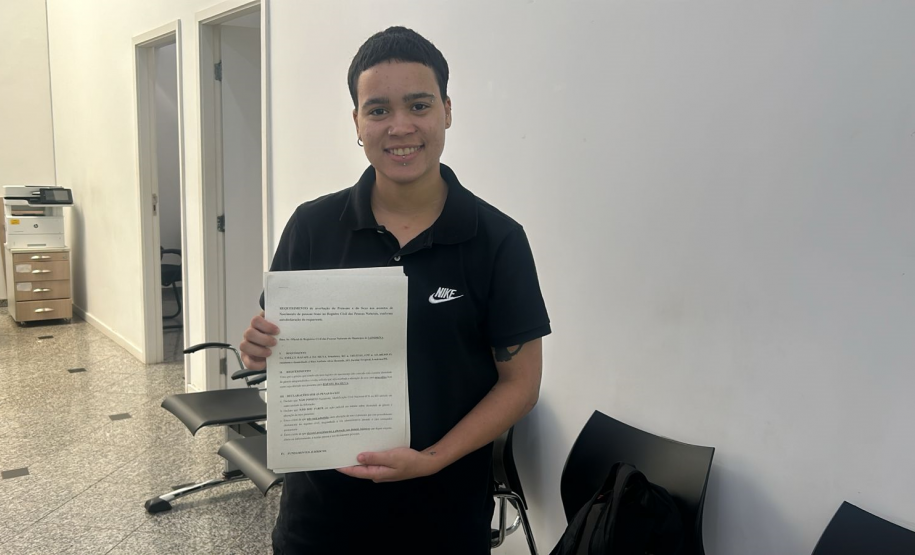 Imagem de uma foto em um ângulo aberto de um usuário segurando seus papéis para a retificação de nome.