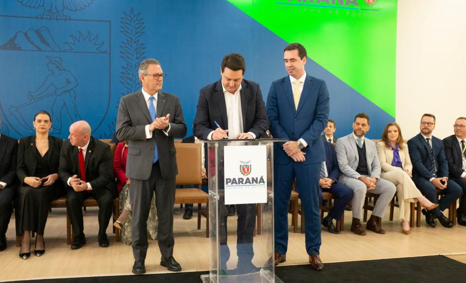 Momento em que o governador do Paraná Ratinhos Junior assina o termo de posse do novo defensor público-geral Matheus Munhoz.