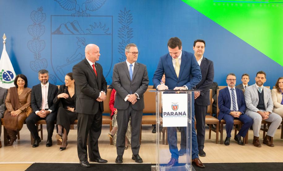 Momento que o novo defensor público-geral Matheus Munhoz assina o seu termo de posse, ao lado do governador, do procurador-geral de Justiça e do presidente do Tribunal de Justiça do Paraná.