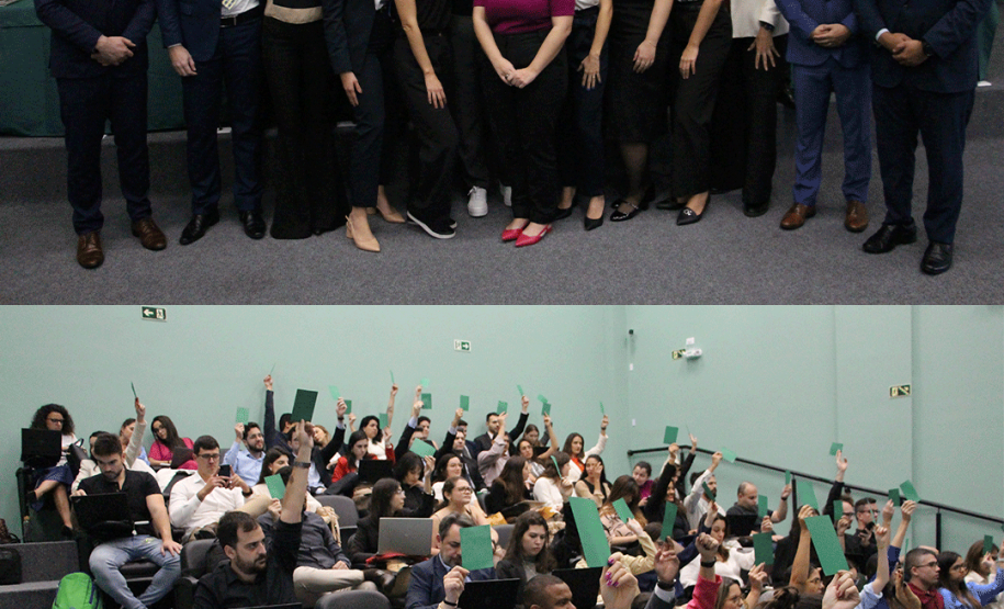 Imagem com a colagem de duas fotos. Na primeira, acima, temos uma foto dos novos defensores que finalziam o curso de formação. Na imagem abaixo, uma foto dos defensores votando para aprovação ou não de uma tese apresentada no evento.