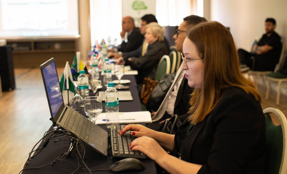 Foto mostrando corregedores e corregedoras assistindo uma apresentação, em foco, uma corregedora usando o notebook.