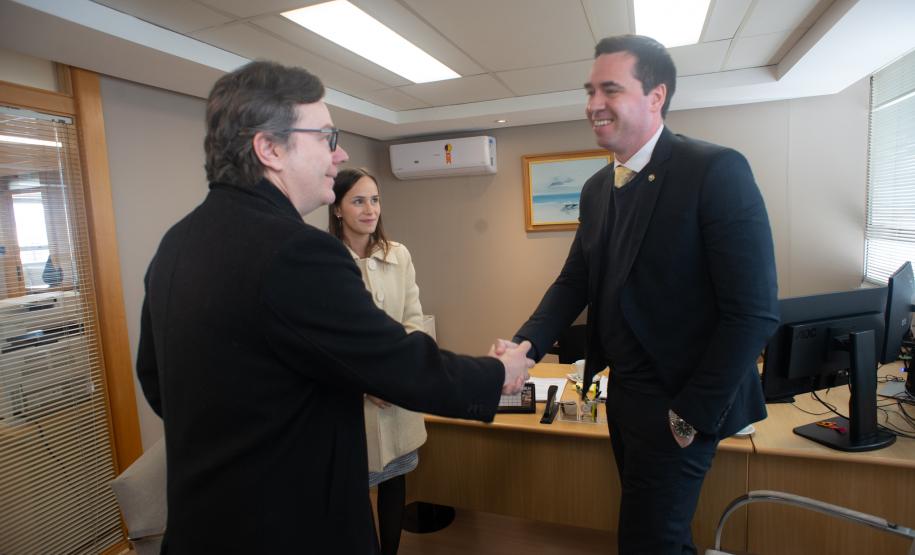 Imagem do Defensor Público-Geral, Matheus Munhoz, acompanhado da 1° subdefensora pública, Lívia Brodbeck, cumprimentando o diretor-geral da Polícia Científica, Luiz Rodrigo Grochocki.