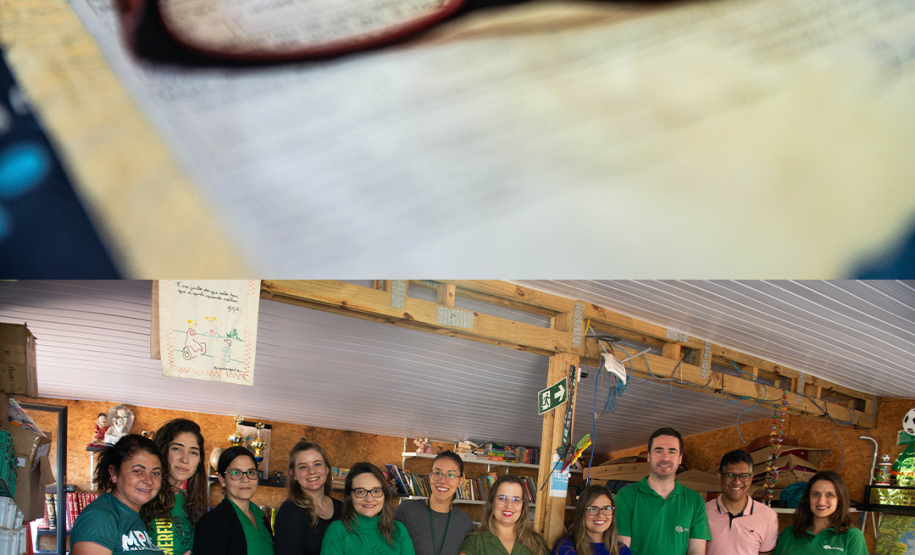 Duas imagens. Na primeira se vê um óculos dobre um documento desfocado e na de baixo se vê a equipe da Defensoria que esteve atuando no mutirão.