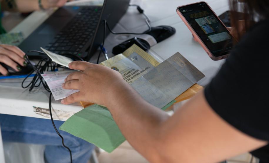 Imagem horizontal colorida em que se vê o detalhe de uma usuária entregando os documentos ao Defensor Público durante o atendimento.
