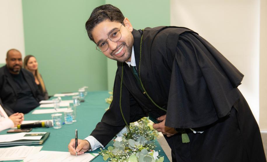 Imagem horizontal colorida onde se vê o novo Defensor Público assinando termo de posse durante a cerimônia.