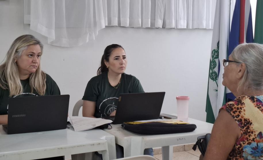 Imagem que mostra um dos atendimentos do evento. Duas pessoas da Defensoria atendem uma senhora.