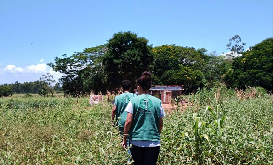 Imagem horizontal colorida em que se vê a equipe da DPE-PR se deslocando a pé na aldeia.
