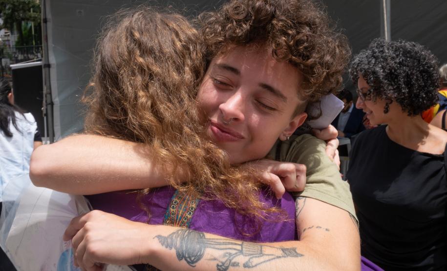 Imagem horizontal colorida em que aparece assistidos se abraçando para comemorar o atendimento realizado pelo Mutirão da DPE-PR.