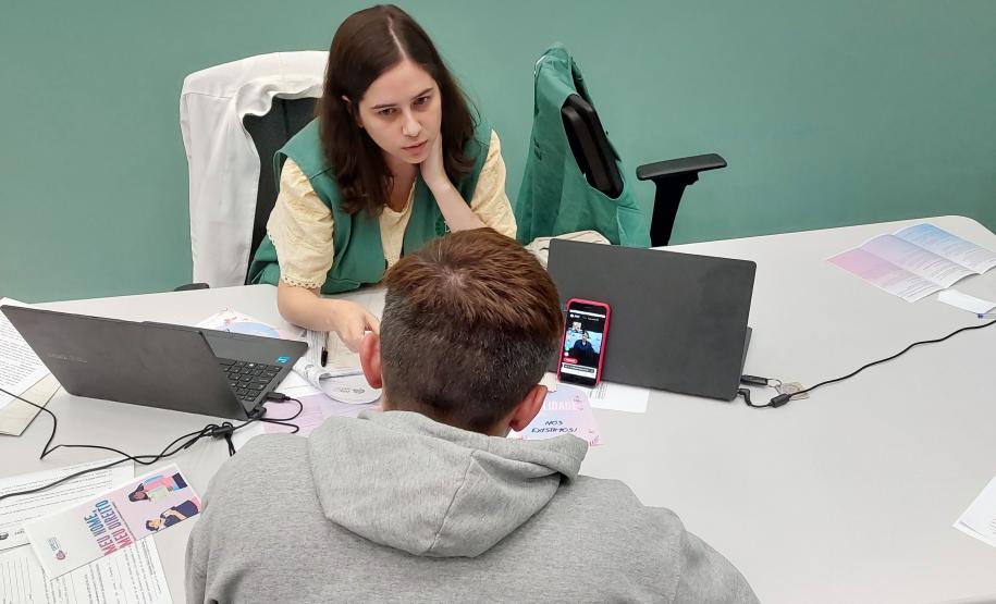 Imagem horizontal colorida em que se vê atendimento a assistido da DPE-PR realizado em Libras com plataforma online Icon.