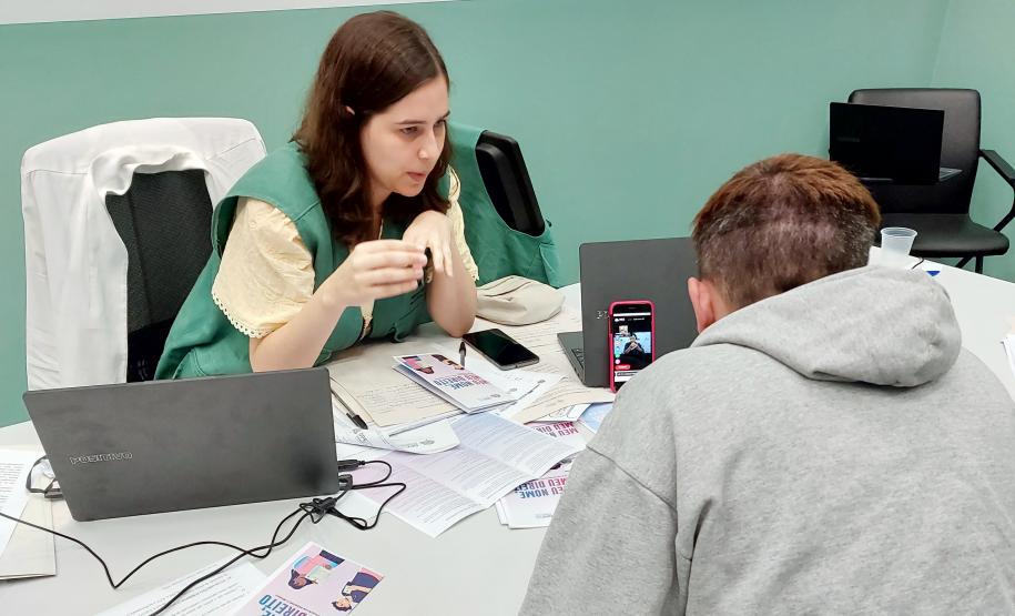 Imagem horizontal colorida em que se vê atendimento a assistido da DPE-PR realizado em Libras com plataforma online Icon.