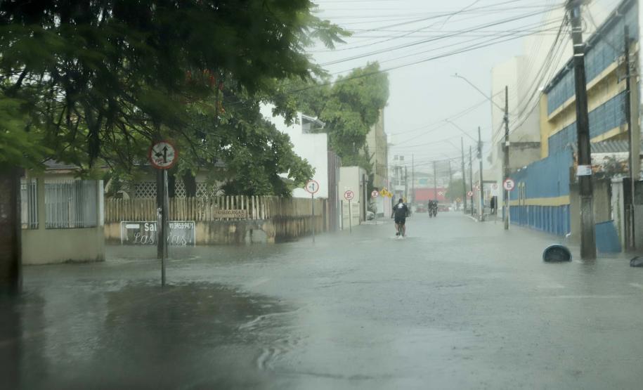 Imagem horizontal colorida mostra rua alagada durante as enchentes no Litoral do Paraná.