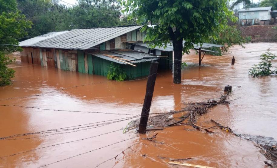 Imagem horizontal colorida em que se vê uma casa de madeira invadida pelas águas barrentas da enchente no Litoral do Paraná.