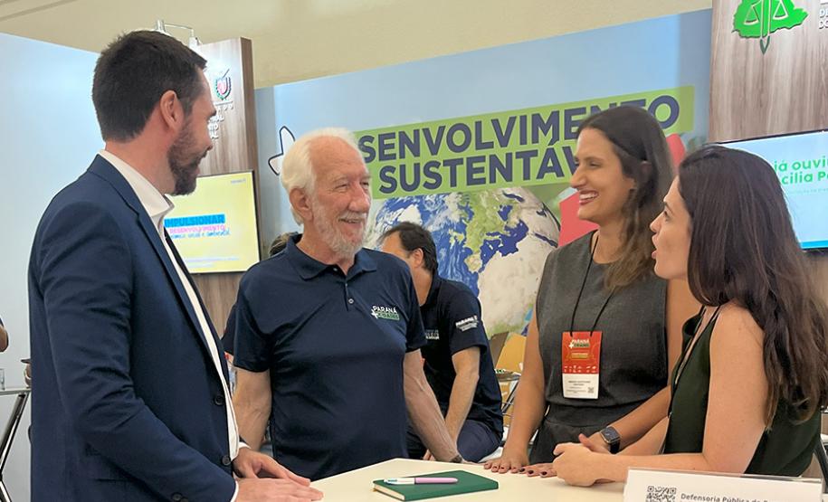 Imagem horizontal colorida em que se vê o vice-governador Darci Piana visitando estande da DPE-PR no Paraná Mais Cidades.