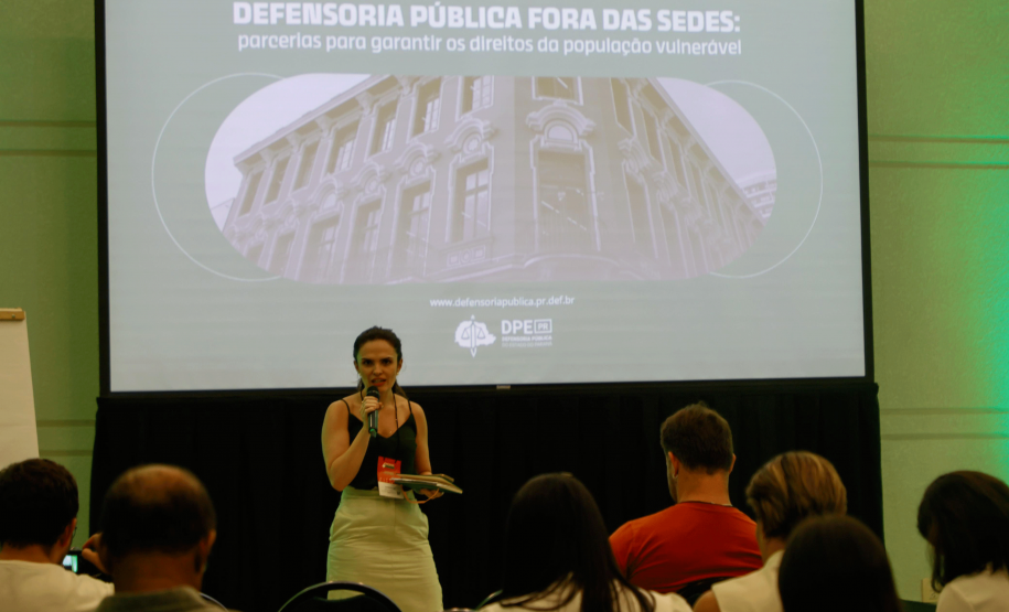 Imagem da defensora Flavia Palazzi palestrando sobre a defensoria durante o evento "Paraná + Cidades"