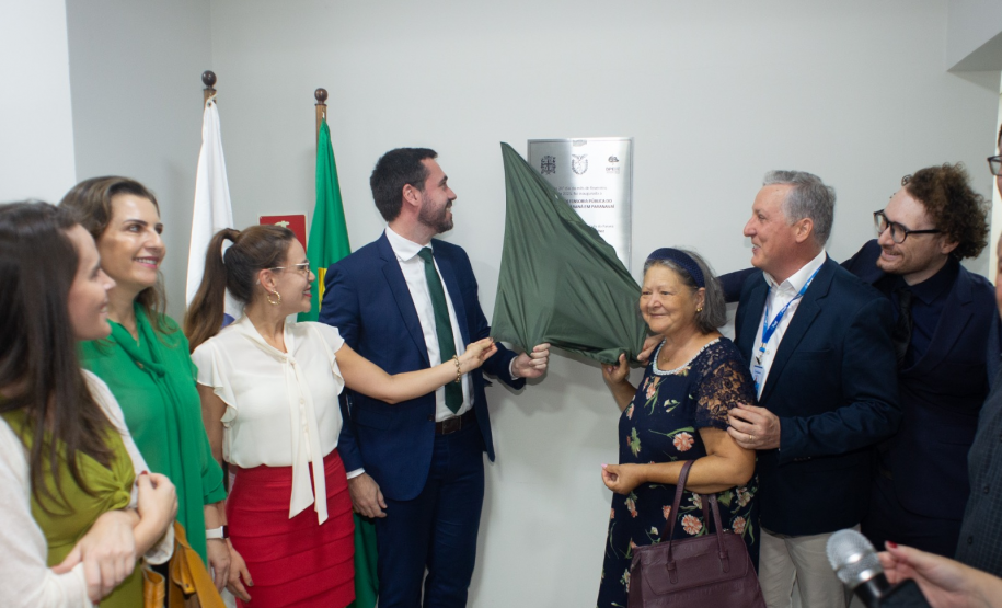 Momento do descerramento da placa de inauguração, com defensores públicos e autoridades reunidos ao redor, aplaudindo o marco da nova sede.