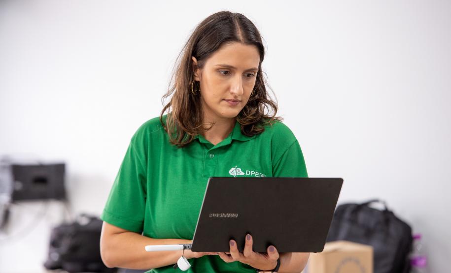 Imagem horizontal colorida em que se vê defensora pública com computador no mutirão de conciliação realizado em Santa Felicidade.