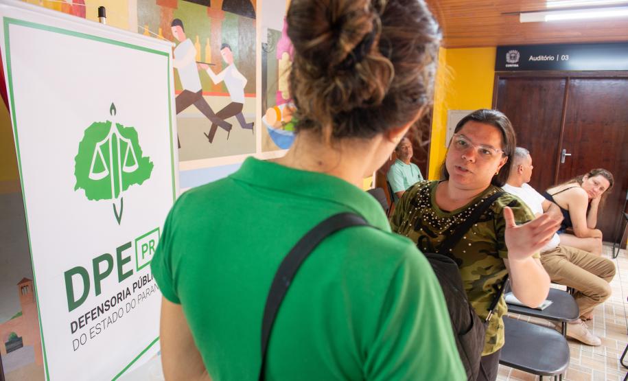 Imagem horizontal colorida em que se vê uma mulher assistida da Defensoria Pública chegando para o mutirão de conciliação realizado em Santa Felicidade.