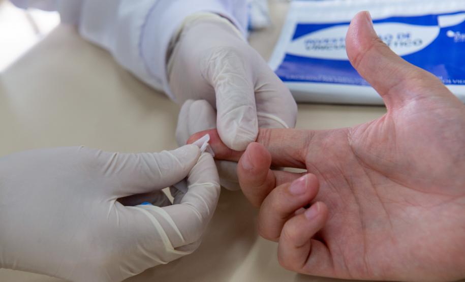 Imagem horizontal colorida em que se vê assistido da Defensoria Pública realizando exame de DNA durante o mutirão realizado em Santa Felicidade.