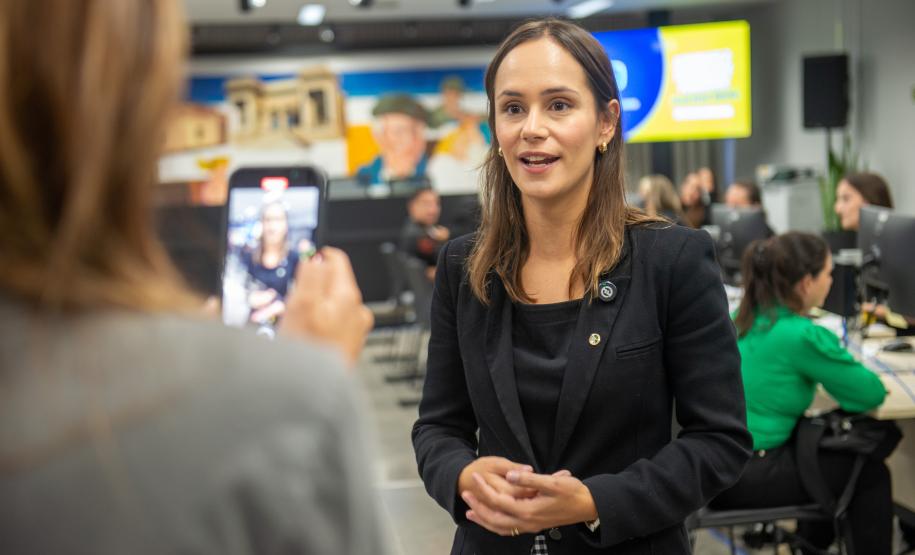 Imagem colorida horizontal em que se vê assistida recebendo a Subdefensora Geral da DPE-PR Lívia Brodbeck falando para a Imprensa durante Mutirão realizado na Câmara Municipal de Curitiba.