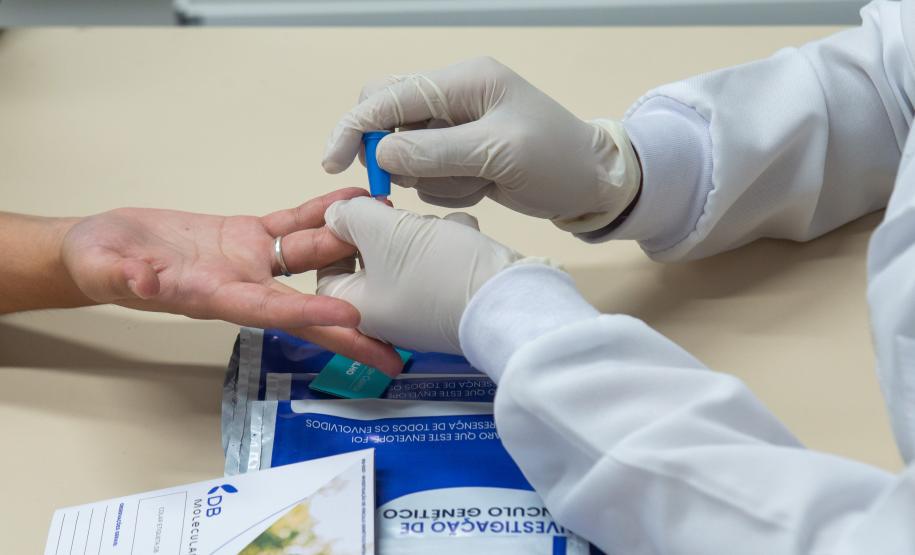 Imagem colorida horizontal em que se vê assistido realizando exame de DNA para reconhecimento de DNA em Mutirão da DPE-PR realizado na Câmara Municipal de Curitiba.