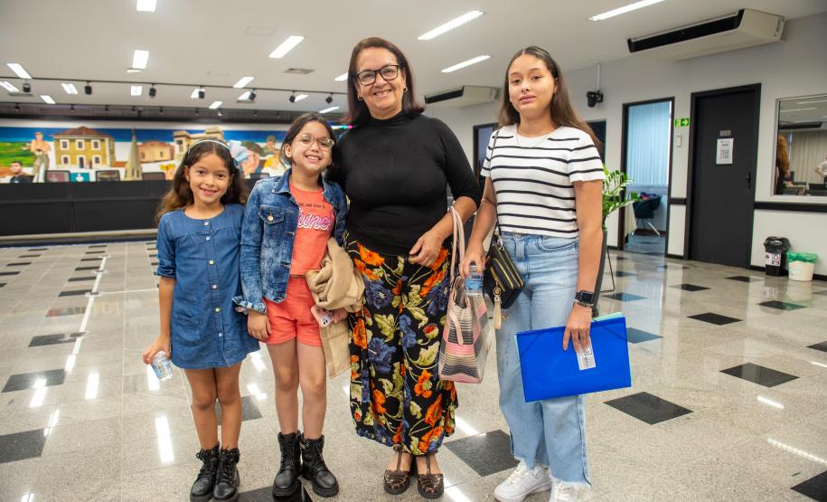 Imagem colorida horizontal em que se vê assistida venezuelana Saida Figueroa e suas netas que receberam atendimento da DPE-PR em Mutirão realizado na Câmara Municipal de Curitiba.