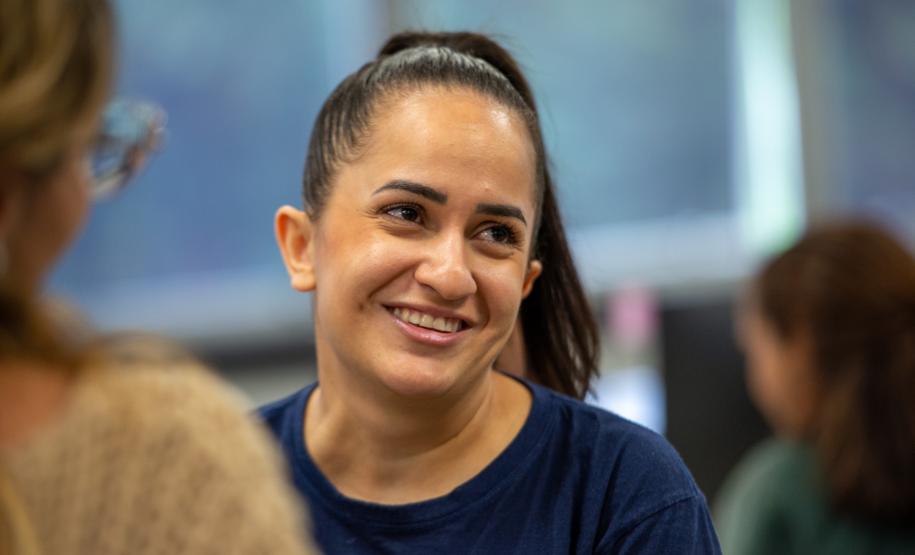 Imagem colorida horizontal em que se vê assistida Maria Janete Silva dos Santos depois de receber o atendimento da DPE-PR em Mutirão realizado na Câmara Municipal de Curitiba.
