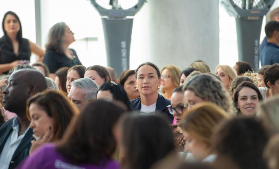 Imagem horizontal colorida em que se vê a ouvidora da DPE-PR em meio ao público durante o lançamento do Projeto Ampara.