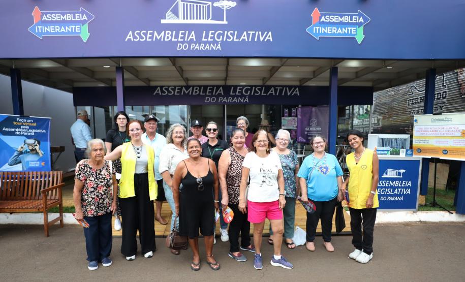 Imagem colorida horizontal em que se vê um grupo de pessoas posando em frente a entrada do evento Assembleia Itinerante, em Londrina.