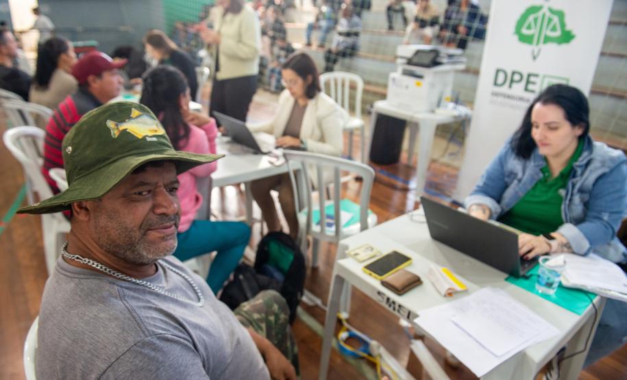 Imagem colorida em que se vê um assistido de chapéu recebendo atendimento jurídico durante Mutirão realizado em Almirante Tamandaré.