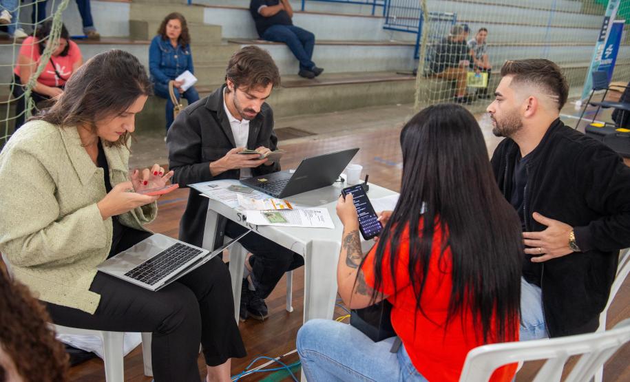Imagem colorida horizontal em que se vê um casal sentado sendo atendido pela equipe da Defensoria Pública em Mutirão realizado em Almirante Tamandaré.