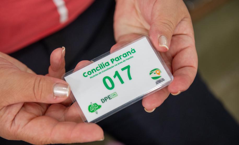 Imagem horizontal colorida em que se vê em clore uma senha nas mãos de uma assistida durante mutirão da DPE-PR em Almirante Tamandaré.