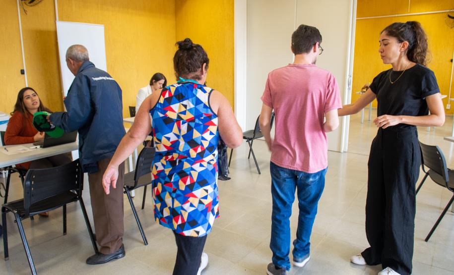 Imagem colorida horizontal em que se vê assistidos passando enquanto ao fundo são realizados atendimentos.