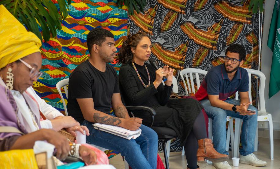 Imagem horizontal colorida em que se vê diálogo de servidores da DPE-PR e representantes do movimento negro.