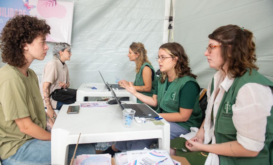 Servidores de colete verde da Defensoria realizam mutirão em tenda montada na rua.