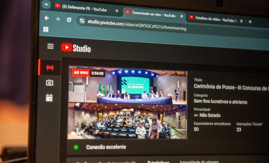 Imagem em que se vê a tela do computador e é possível ver a tela de transmissão ao vivo do evento no YouTube.