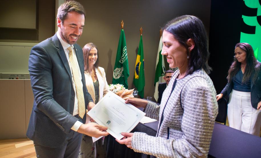 Imagem mostra nova servidora recebendo termo de posse das mãos do DPG.