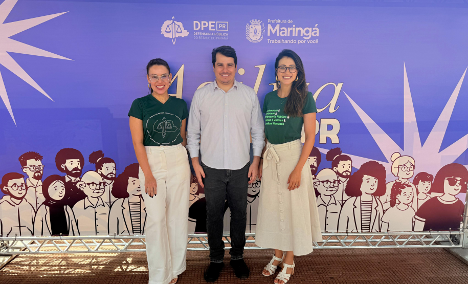 Três pessoas posam em frente a um banner do programa Agiliza da Defensoria Pública do Paraná.
