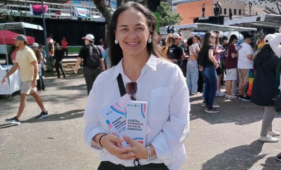 Ouvidora geral da Defensoria mostrando materiais informativos sobre a retificação de prenome e gênero.