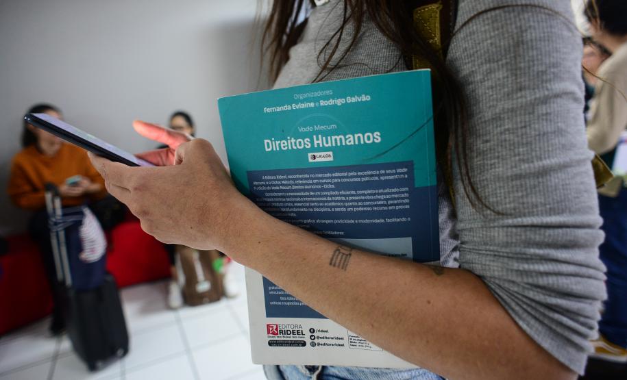 Imagem mostra o braço de uma mulher em close segurando livro jurídico para consulta antes da prova do V Concurso Público para Defensora e Defensor Público do Estado do Paraná.