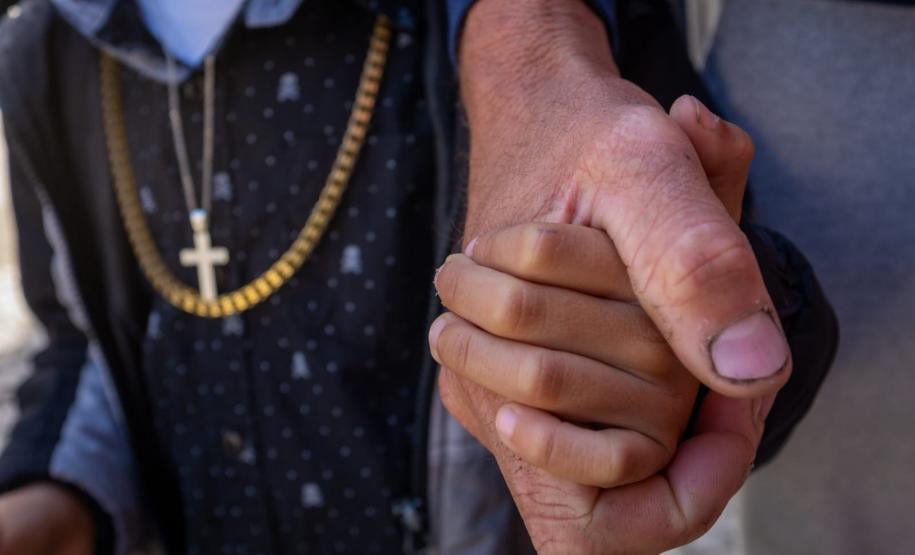 Detalhe da mão do pai segurando a mão do filho.