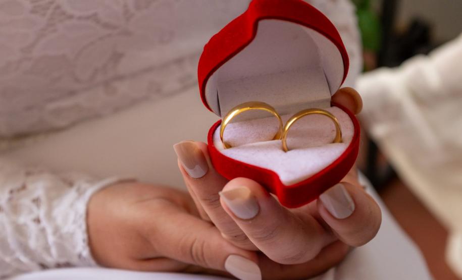 Detalhe da noiva mostrando o par de alianças para a foto.