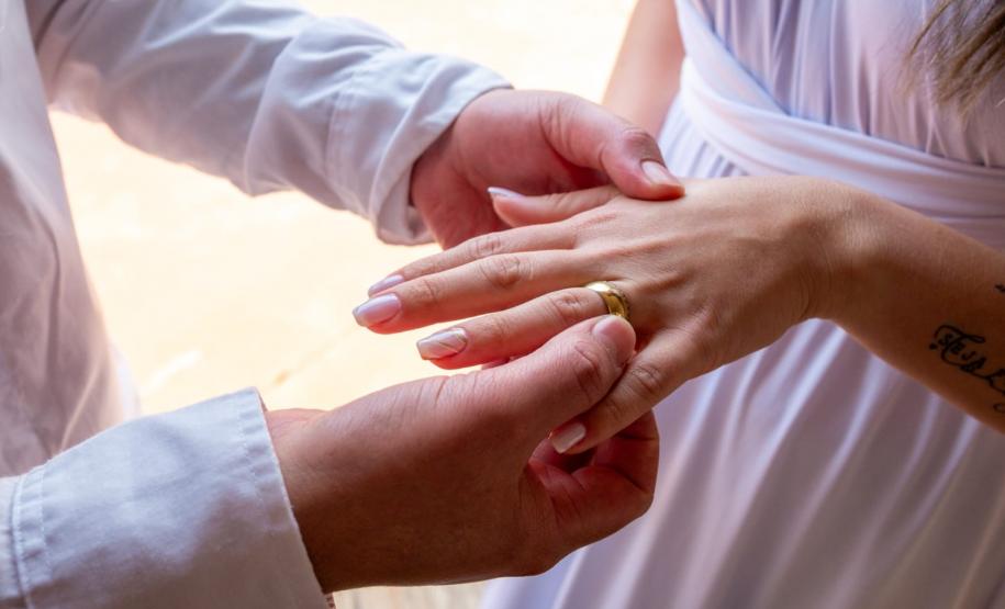 Detalhe do noivo colocando aliança no dedo da noiva.