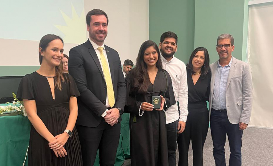 Nova defensora pública recebe sua carteira funcional ao lado de representantes da instituição e familiares.