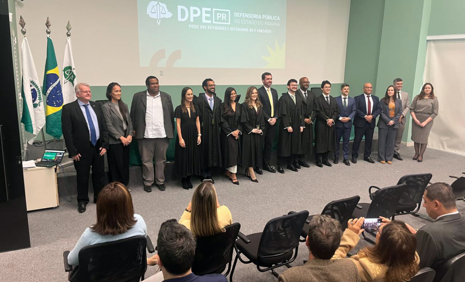 Novos defensores públicos empossados posam ao lado de representantes da instituição ao fim da cerimônia no auditório da instituição.