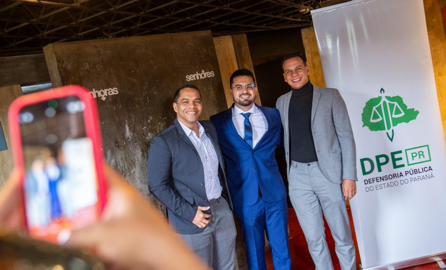 Família posa com defensora empossado ao lado do banner da DPE-PR.