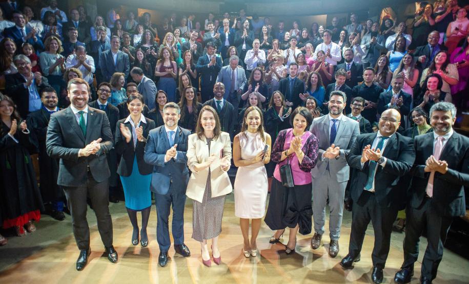 Representantes da DPE-PR posam diante do público no Teatro Paiol ao final da cerimônia.