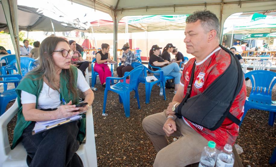 Servidora da DPE-PR realiza atendimento a um homem com tipoia no braço.